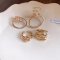 Macro detail of four gold-plated hollow rings featuring oval and cross-wound minimalist designs - Four-Piece Set / Gold