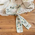 Detailed view of a holiday style fabric necklace with floral print and resin buckle. - Green Floral