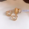 Close-up detail of minimalist gold hollow-out and cross-wrap rings with irregular textures - Four-Piece Set / Gold