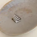 Dettaglio macro di un orecchino a clip a stella con zirconi su un piatto di ceramica. - Stile Stella Multistrato a Spirale (5#) / Pezzo Singolo / Argento