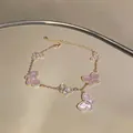 Nahaufnahme eines eleganten goldenen Schmetterlingsarmbands mit rosa Steinen und Zirkonia. - Gold-Rosa