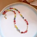 Close-up of multi-color stone beaded necklace with white pearl accents and gold clasp. - Necklace / Colorful
