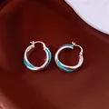 Macro view showing the intricate turquoise bead inlay on silver vintage hoop earrings. - Blue