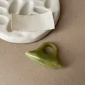Close-up of minimalist green marble pattern resin ring on neutral textured background - Green