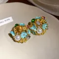 Detailed macro shot of vintage floral stud earrings with pearls and colorful crystals - Gold / Blue