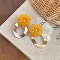 Close-up of elegant resin orange flower earrings with gold-finished oval rings - Yellow Oval Style