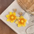 Detailed view of handmade yellow resin flower dangle earrings with elegant gold rose studs. - Yellow Orange Layered Style