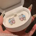 Close-up of macaron colored pearl stud earrings with rhinestones in a white gift box - Blue