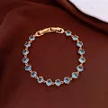 Detailaufnahme des 18k vergoldeten Armbands mit runden blauen Zirkonia auf brauner Seide. - Gold-Blau