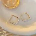 Makrodetail der geometrischen Rautenohrringe mit klaren Glasperlen auf Golddraht. - Raute Weißer Stil (Style 3)