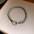 Detailansicht eines grauen Perlenarmbands mit glitzerndem Schweinenasen-Verschluss - Strass-besetzter Ankerketten-Stil / Silber mit grauer Perle