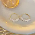 Elegante goldfarbene Creolen mit klaren Glasperlen auf einem cremefarbenen Keramikteller - Runder Stil (Style 6) / Gold-Weiß