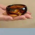 Primer plano de un brazalete retro de acrílico ambarino veteado con acabado pulido brillante. - Café Degradado