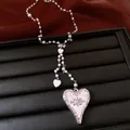 Close-up detail of retro heart pendant necklace with pearl beads on black display - Necklace / Silver-White