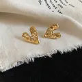 Macro detail of elegant gold-tone heart-shaped stud earrings with a unique crumpled texture - Stud Earrings / Gold