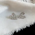 Detailed macro view of silver stud earrings featuring a unique pleated heart shape. - Stud Earrings / Silver