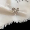 Close-up of a silver wrinkled heart ring on a cream textured fabric background - Open Ring / Silver