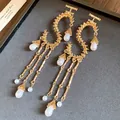 Primo piano di orecchini a frange in metallo dorato con eleganti perle a goccia d'acqua. - Oro