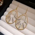 Detailed view of rhinestone water drop earrings with bohemian thread wrapping on velvet - Earring Hooks / Gold