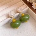 Close-up of olive green and cream resin drop earrings with silver needle in jewelry tray - Silver Post Green Yellow