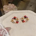 Vista dettagliata di orecchini a lobo dorati con coccinelle in smalto e accenti floreali in zircone. - Ghirlanda di Coccinella e Fiore / Oro