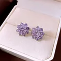 Detailed view of elegant purple zircon flower earrings in a cream jewelry box - Purple