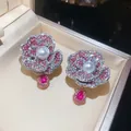 Detailed macro view of camellia flower earrings with pink rhinestones and central pearls - Pink
