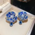 Macro view of blue crystal flower earrings with central pearl and teardrop charm - Blue
