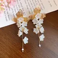 Elegant gold-tone floral tassel earrings with white resin flowers and pearl accents. - Silver Post Flower Tassel Style (HE34213) / Gold-White