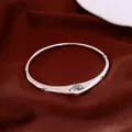 Close-up of elegant vintage style silver zircon bangle on smooth red silk fabric - Bangle / Silver