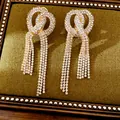 Detail view of luxurious gold-toned knotted earrings with sparkling rhinestone tassels - Knot Tassel Style (HE34116) / Gold