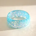 Close-up detail of blue resin bangle featuring iridescent flakes and sunlit caustic reflections - Iridescent Blue