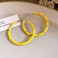 Primer plano de pendientes de aro amarillos con lunares azules y agujas de plata - 5cm de Diámetro / Amarillo con lunares