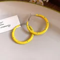 Primer plano de pendientes de aro de esmalte amarillo con lunares azules y aguja de plata - 4cm de Diámetro / Amarillo con lunares