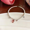 Close-up detail of pearl necklace with pink resin strawberry charm and zircon hearts - Silver-White-Pink