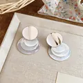 Dettaglio di orecchini con dischi di conchiglia e finitura in metallo spazzolato. - Placcato Argento Bianco