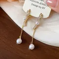 Detailed view of 18K gold-plated zircon earrings featuring elegant dangling pearls - Gold-White