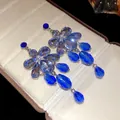 Detailed macro view of elegant blue crystal flower earrings with teardrop pendants - Blue