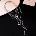 Dettaglio della collana a strati argento con ciondoli a croce e cuore su sfondo nero. - Colorato / Argento