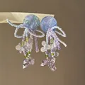 Gros plan sur des boucles d'oreilles en perles lilas avec des cristaux féeriques - Boucles d'oreilles à clip / Bleu Violet