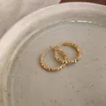 Detailed macro shot of French vintage gold hoop earrings with diamond-cut texture - Gold