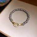 Luxuriöses Armband mit grauen Perlen und einem funkelnden Zirkonia-Rundverschluss-Detail - Gold-Grau