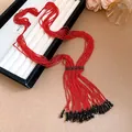 Detailansicht einer handgefertigten mehrreihigen roten Perlenkette mit schwarzen Quasten. - Rot