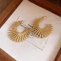 Detailed view of gold sunburst C-shaped hoop earrings with radial metal beams - Gold
