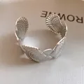 Detail view of a silver-finish open cuff bracelet featuring intricate seashell textures. - Ripple Hollow Splicing Style (4)