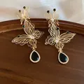 Detail shot of vintage hollow butterfly earrings with black teardrop crystal pendant - Black Water Drop (HE34287) / Gold