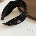 Detail view of black polka dot headband with pleated fabric and a rhinestone heart - Black