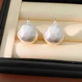 Detailed macro shot of silver-colored brushed geometric metal ear clips in a box. - Silver