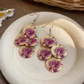 Dettaglio di orecchini in stile cinese con stampa di orchidea viola su dischi dorati - Viola