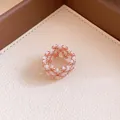 Nahaufnahme eines roségoldenen und weißen geflochtenen Perlenrings mit eleganter Textur - Geflochtener Ring / Gold mit Weiß